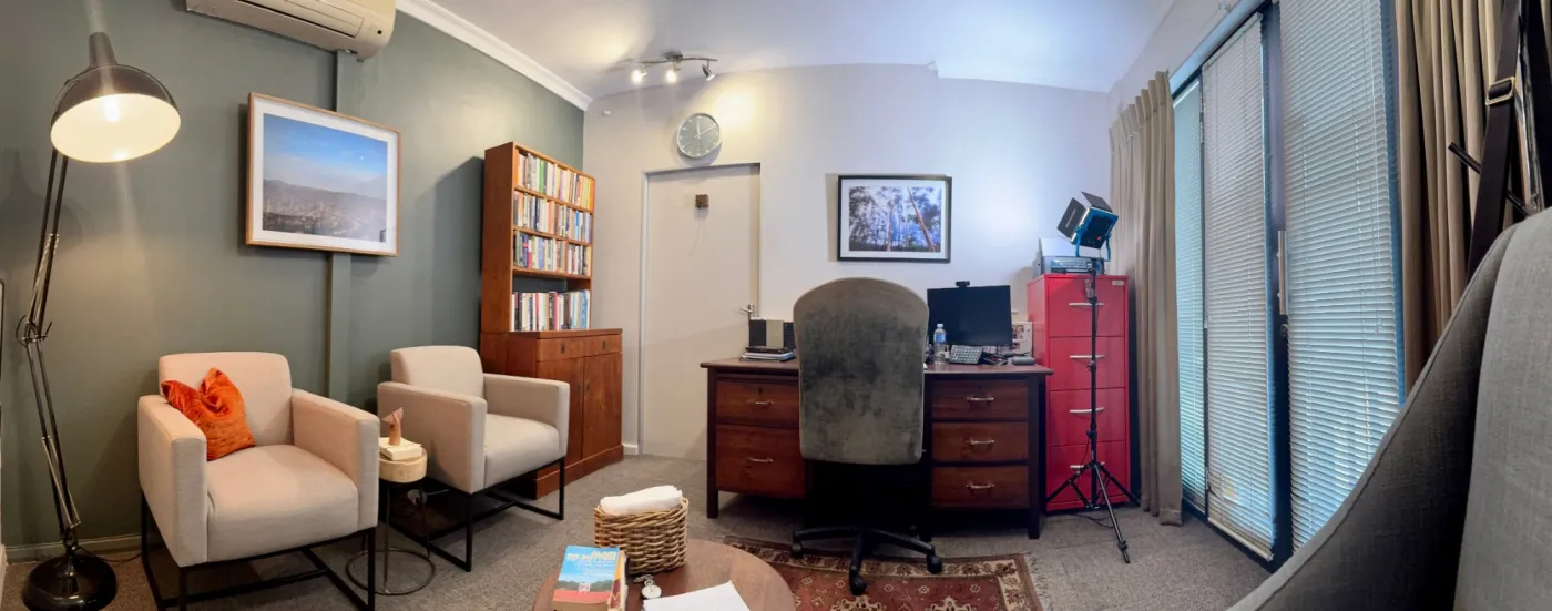 The counselling room: two armchairs and a bookcase against a green wall, with a desk and filing cabinet by the window