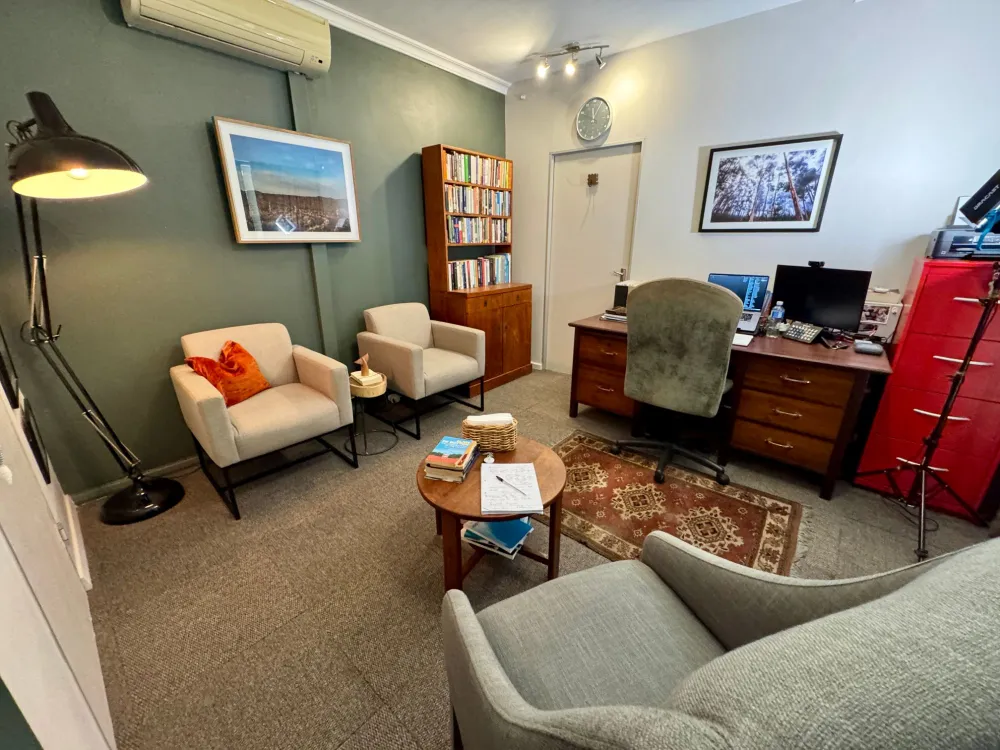 The counselling room: two armchairs and a bookcase against a green wall, with the desk and filing cabinet beyond