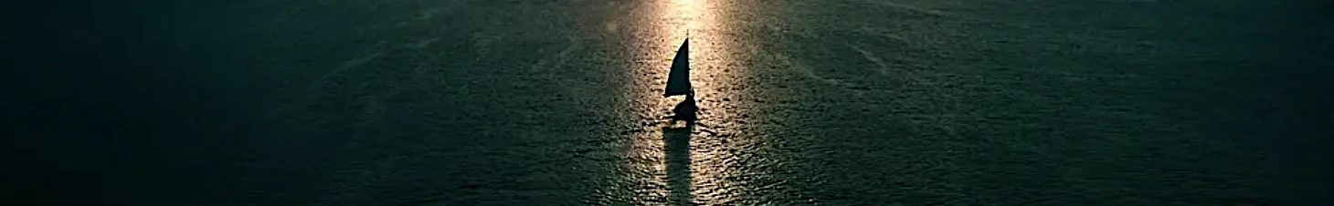 A lone sailboat heading into the sunlight on open water